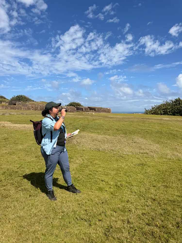 Mariela Gómez observa la fauna con binoculares en los terrenos del San Juan National Historic Site